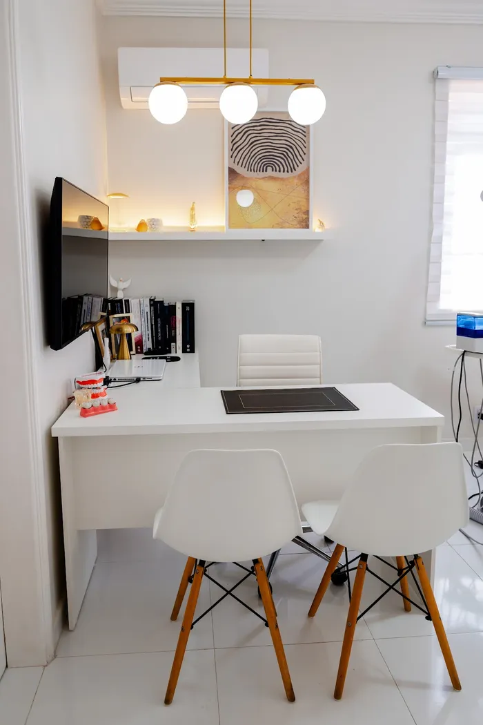 Mesa branca com cadeiras e monitor no consultório